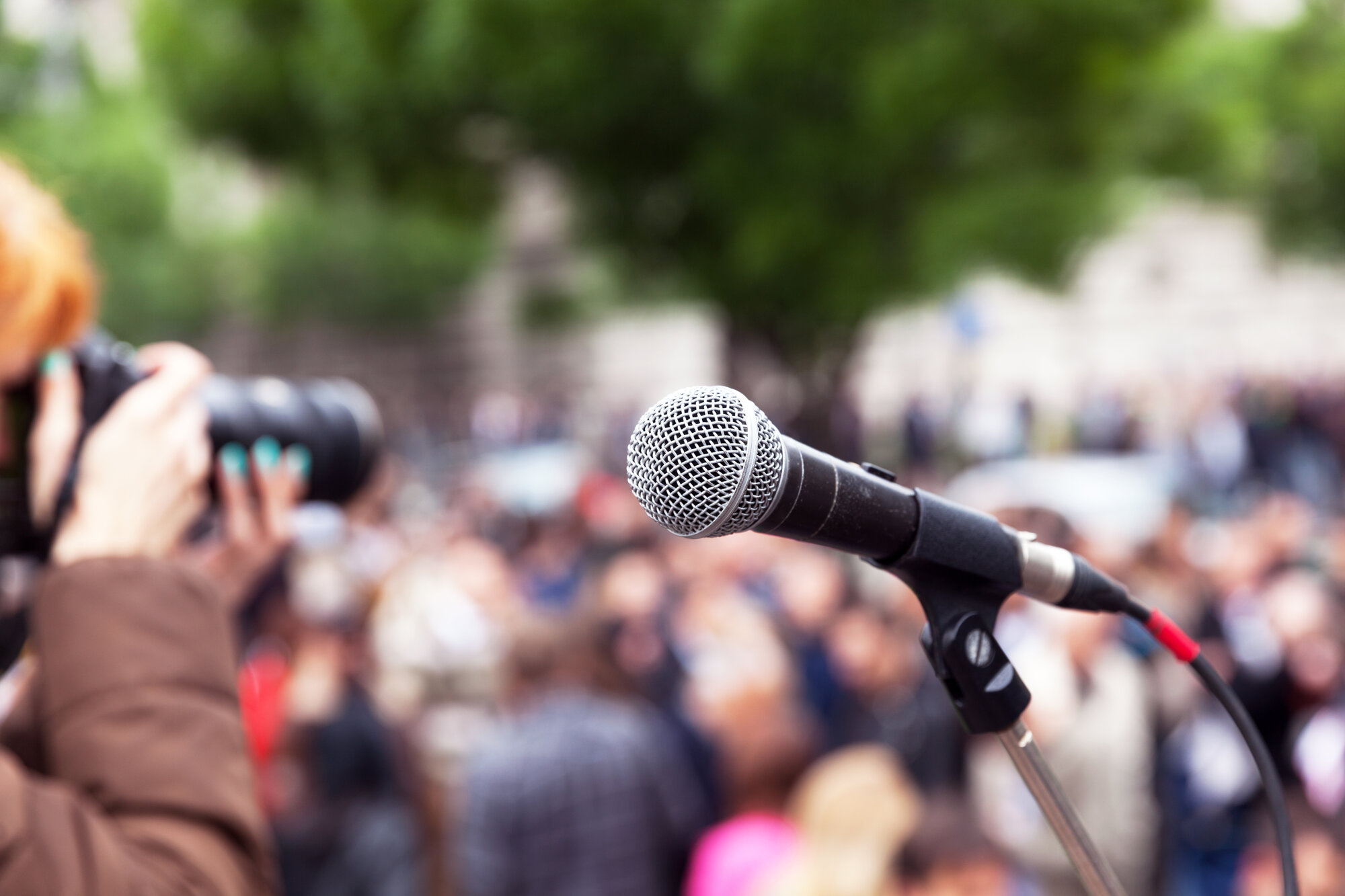 Microphone,In,Focus,,Blurred,Female,Photographer,At,Work,In,The